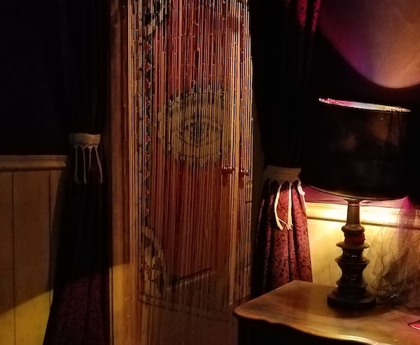 A table lamp next to a doorway with a beaded curtain featuring an open eye.