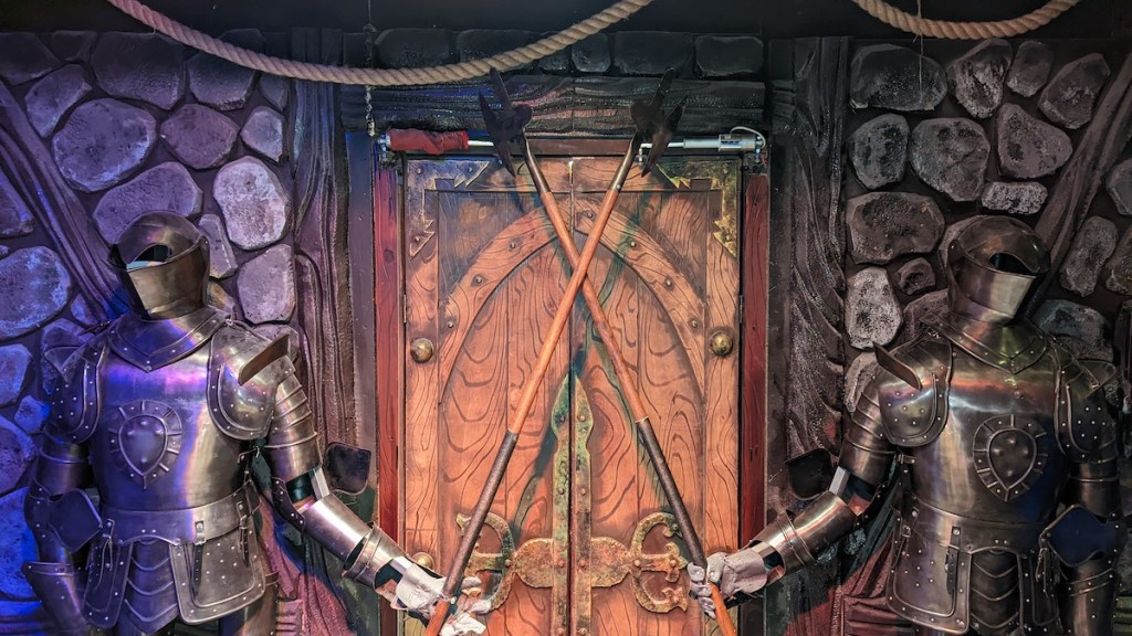 Two knights holding crossed poleaxes, guarding a castle door.