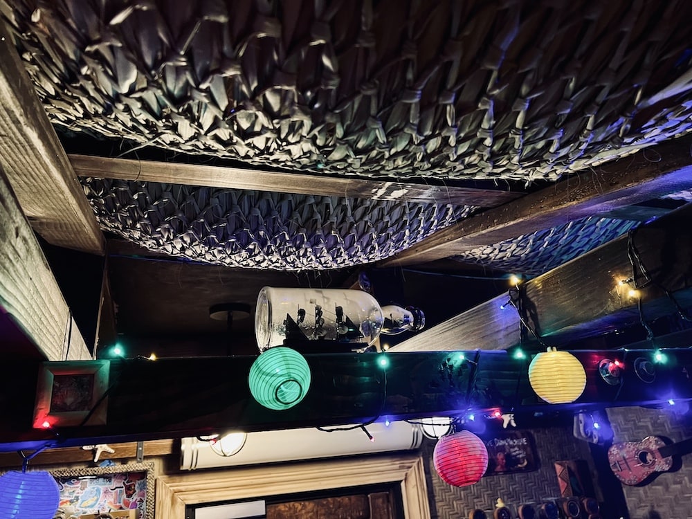 A woven roof to a tiki bar. In the rafters are lights and a ship in a bottle.