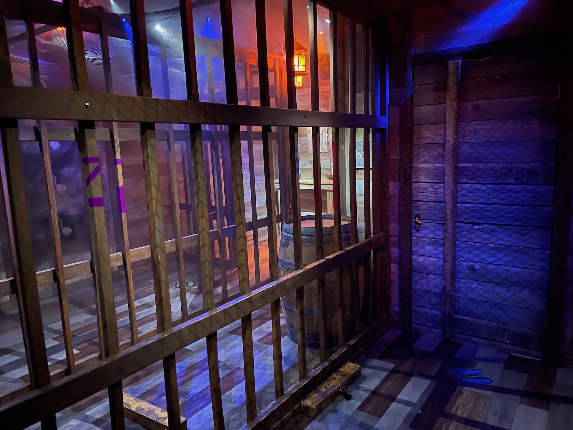 view from inside the brig of a pirate ship with wooden bars and a wooden barrel