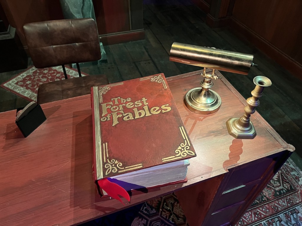 A large tome labeled, "The Forest of Fables" sitting atop a desk in a study.