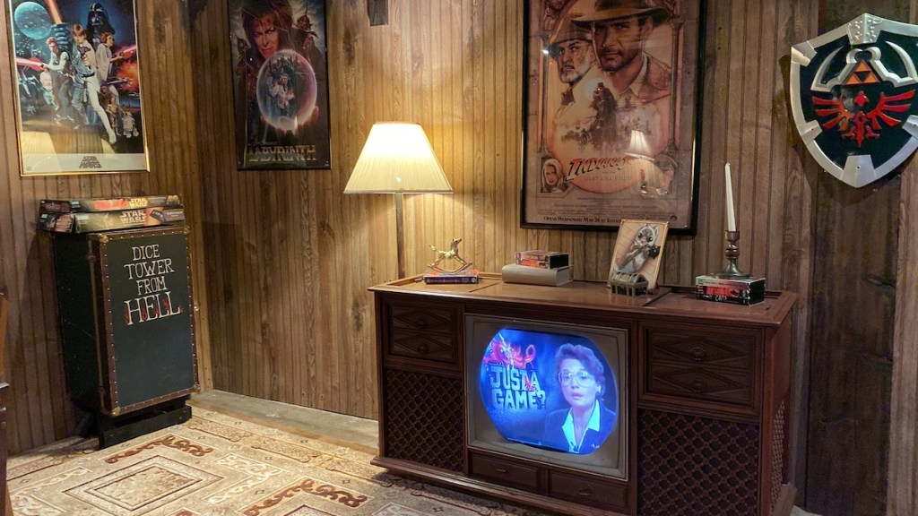 An 80s basement with wood panelling, movie posters, and a shield from Zelda.