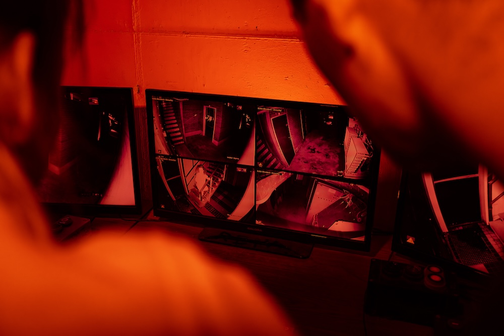 Two people look at a series of security feeds.
