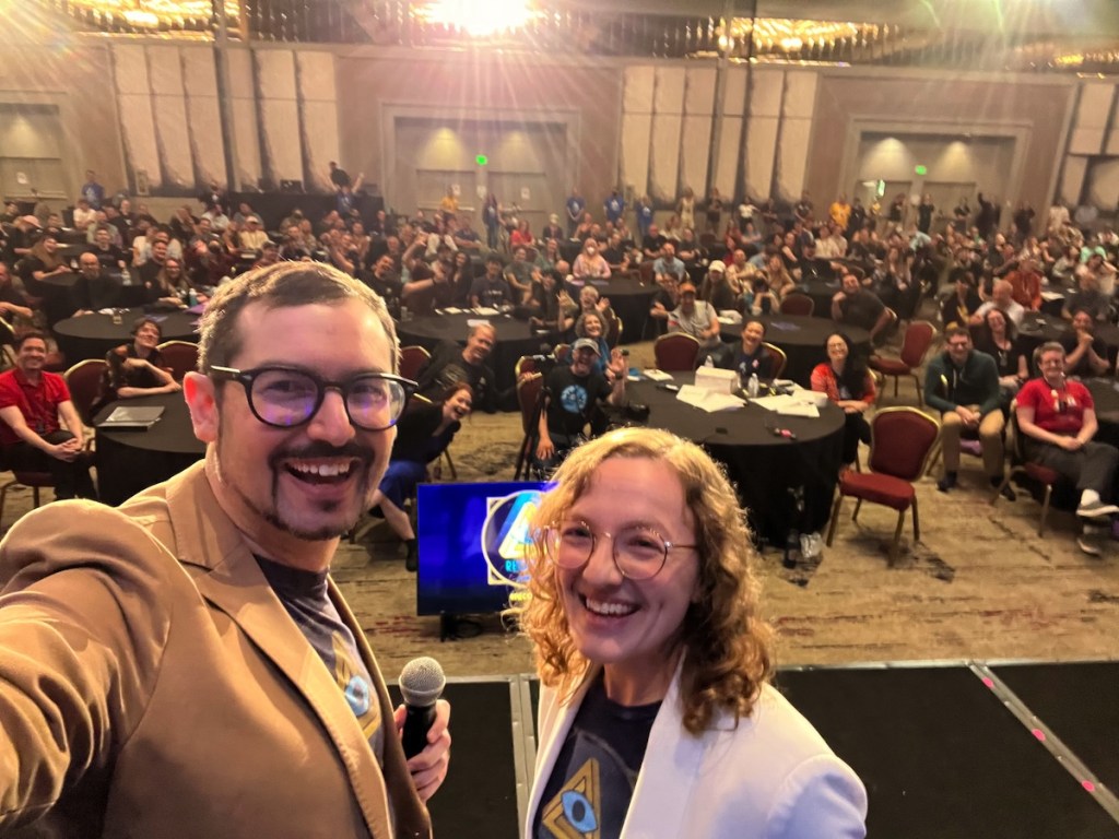 David and Lisa on-stage at RECON taking a selfie of a very full audience.