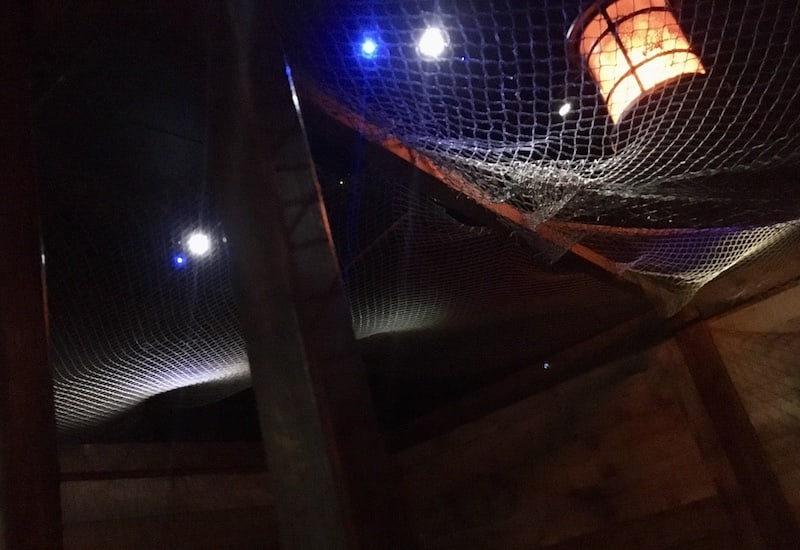 In-game: The ceiling of a ship. A lantern hangs above cargo nets.
