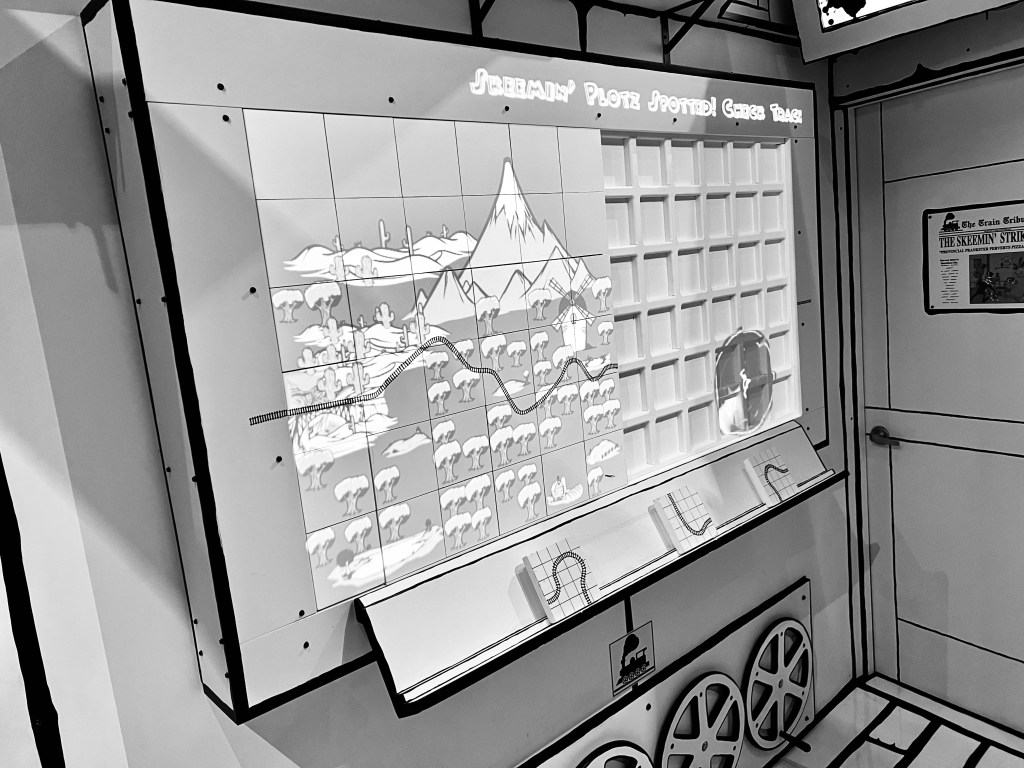 A black and white map with a train line running through it. The second half of the map is incomplete and there are loose pieces to fill it in.