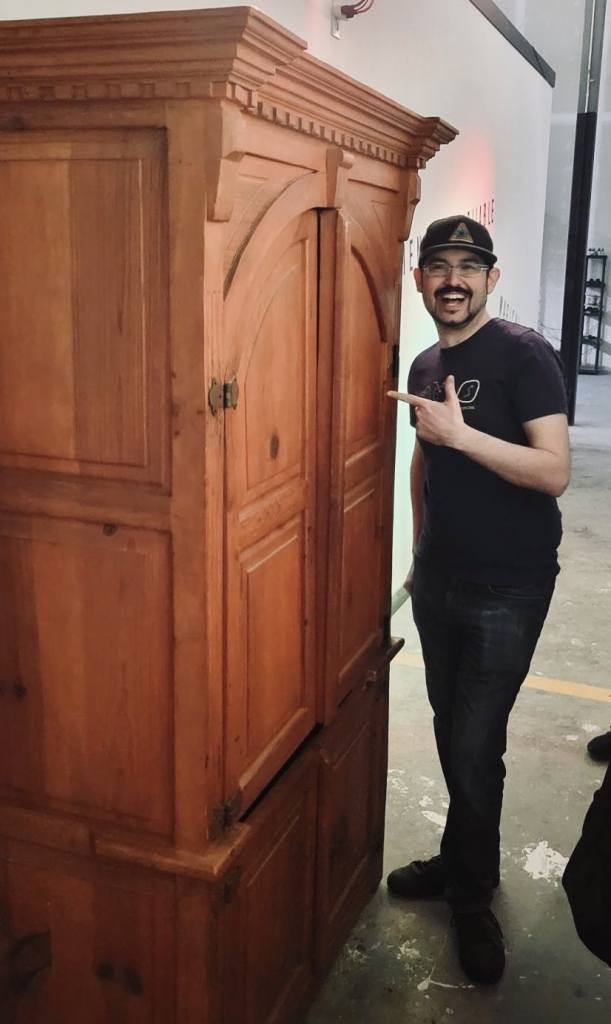 David standing next to a large, wooden wardobe and pointing at it excitedly.