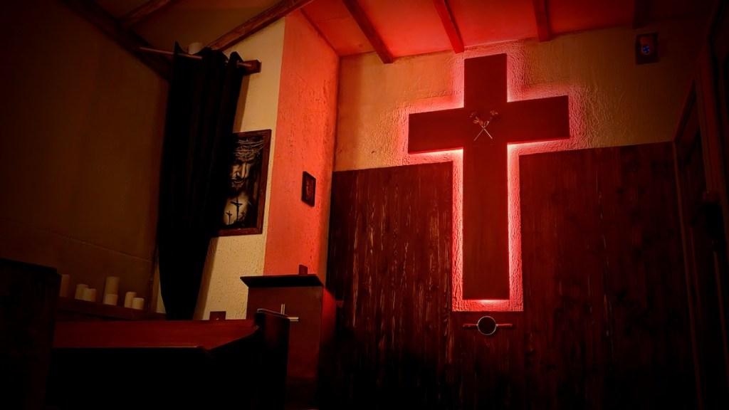 A glowing red cross on a wall in a church.