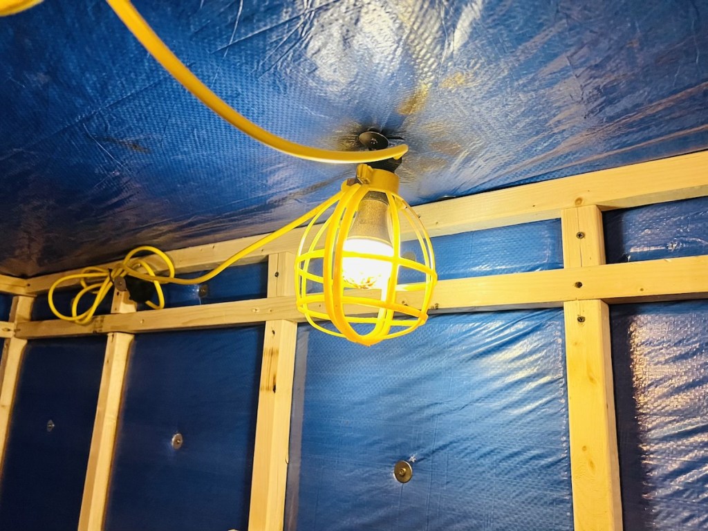 Close up of a yellow shrouded light against blue tarp and wood framed interior of an arctic research facility.