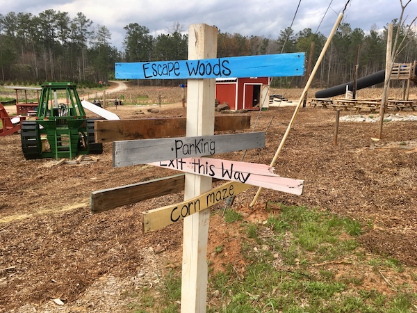 A sign pointing in many directions towards escape woods, parking, a corn maze, and the exit.