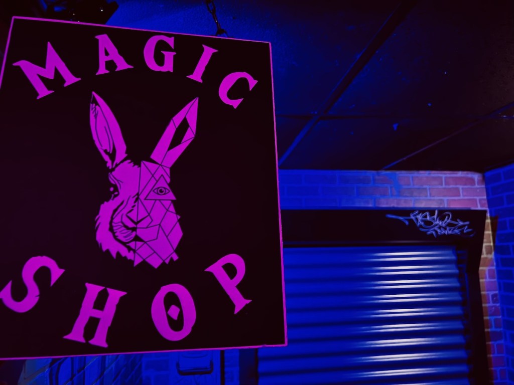 The geometric rabbit sign for Fenway's Magic Shop beside a loading dock.
