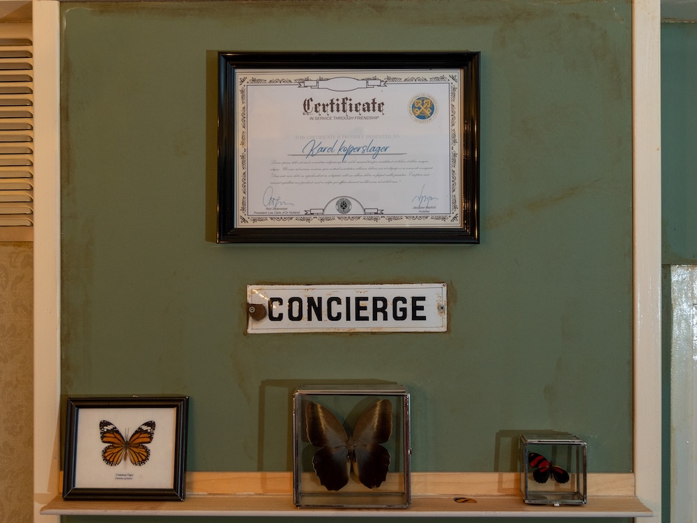 A concierge station with a certificate hanging on the wall above a few preserved butterflies.