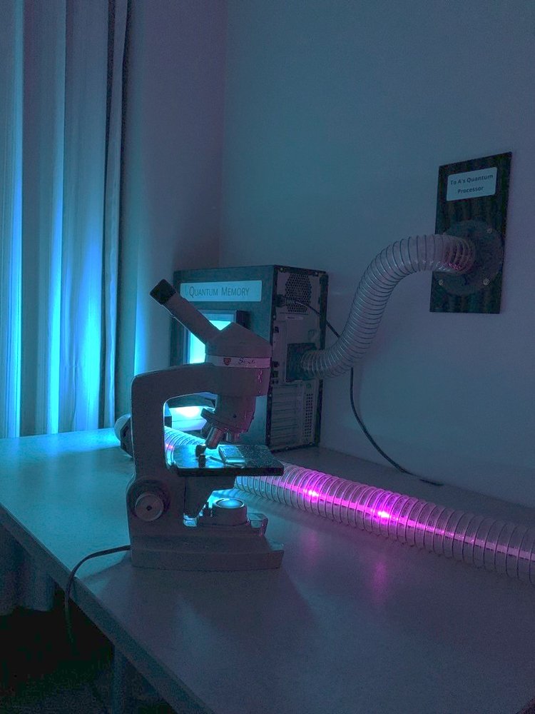 Microscope in frong of a computer with large tubes coming out and attached to the wall