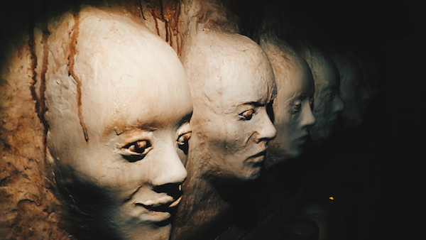 In-game: a weathered wall of creepy plaster faces.