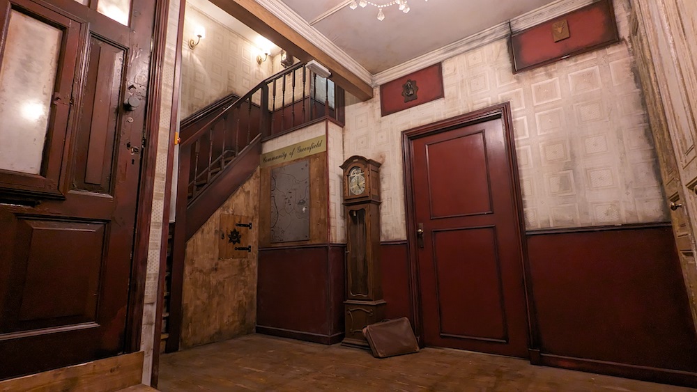 Hallway of an old, rundown home. A grandfather clock sits in the corner beside the staircase.