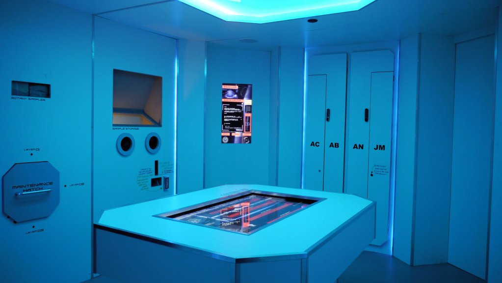 futuristic looking room, blue walls with monitors and screens on the walls