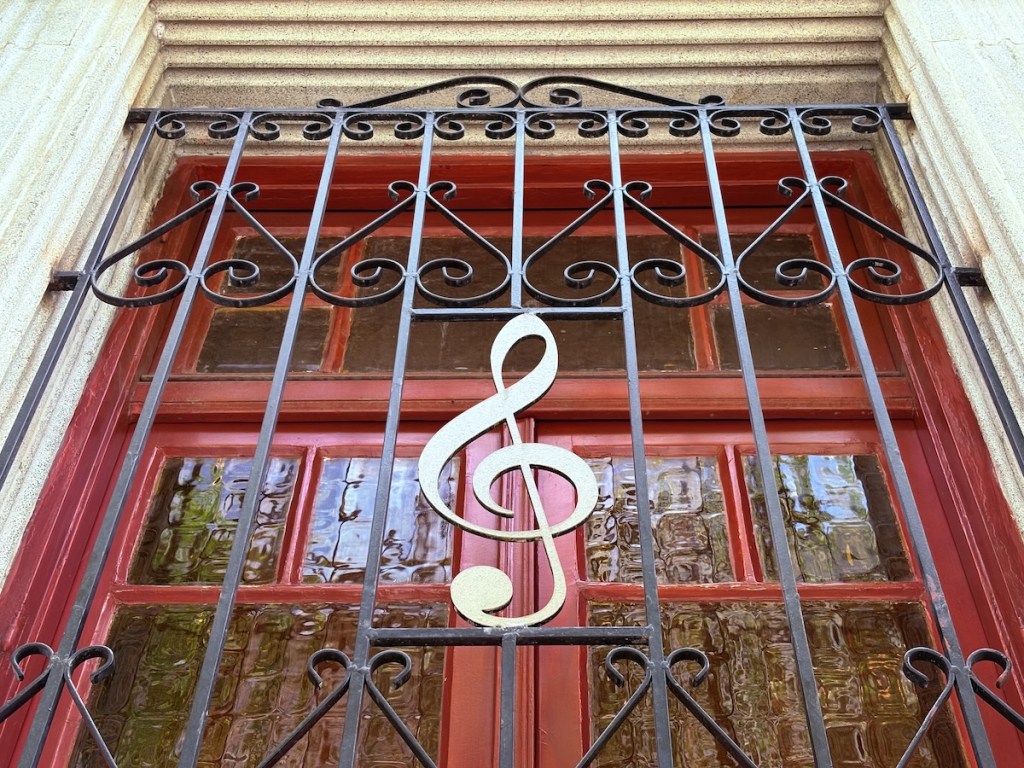 A red window barred up with black metal and a treble clef.