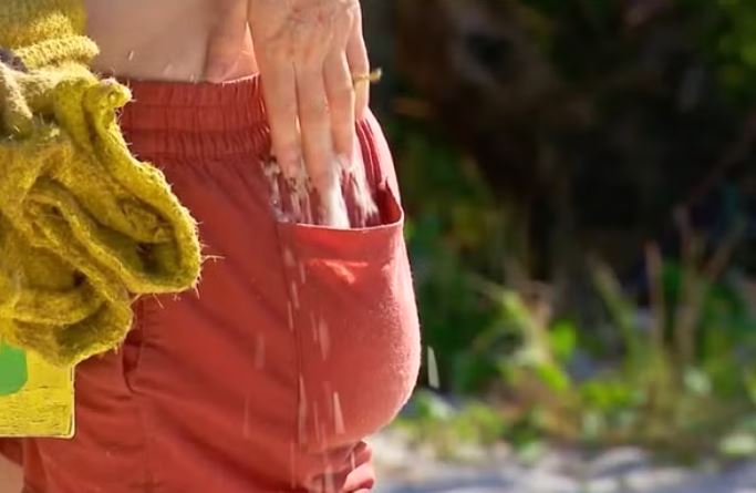 close up of a hand dropping rice into the pocket of red shorts