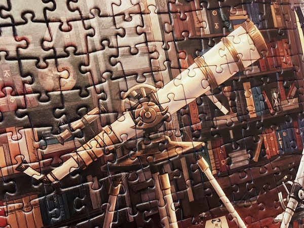 Portion of an assembled jigsaw puzzle featuring a beautiful telescope in a warm book-filled study.