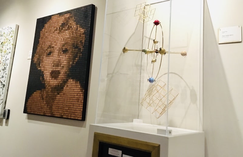In-game: A portrait of Marilyn Monroe made out of pennies beside a geometic sculputre.