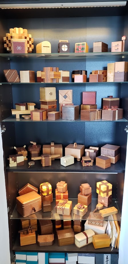 Shelf full of mechanical wooden puzzles, about 10-15 on each shelf.