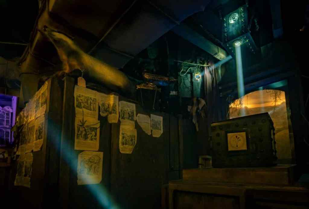 dark room with papers stuck to the wall and a mysterious box emitting light hanging from the ceiling.