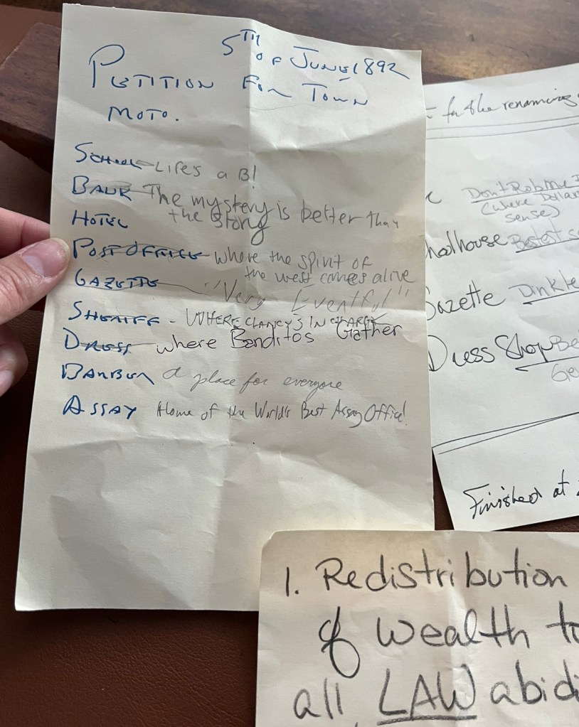 A series of handwritten notes from Ghost Town Alive. The top says "petition for town motto" under is a list of locations and different suggestions for town mottos like "Very Eventful", "Where Bandits gather" and "The Mystery is better than the Story"