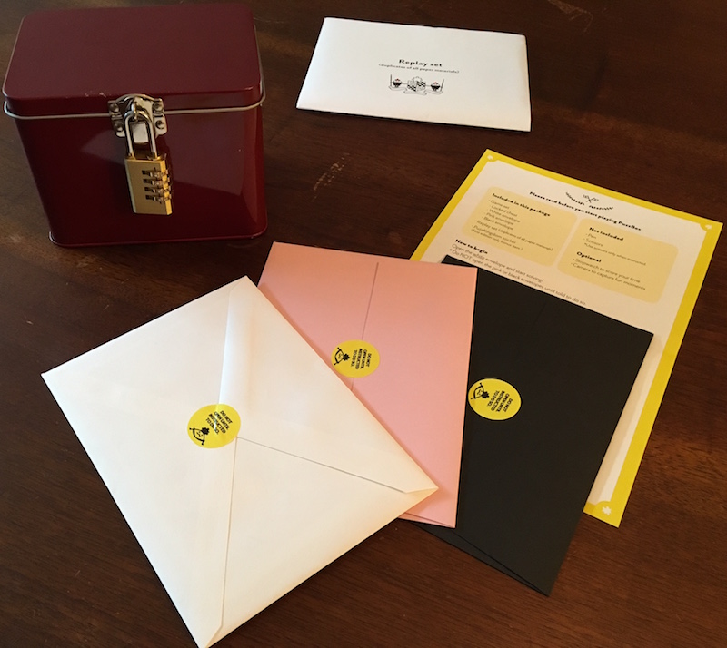 The entire game's contents. A lockbox, three envelopes, a yellow sheet of paper, and a replay set.