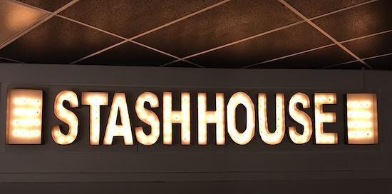 In-game: a glowing set of lights that read "STASHHOUSE"