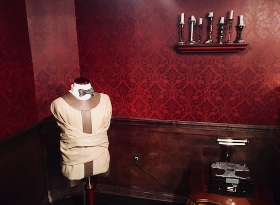 A straight jacket is affixed around a bow tied mannequin. 
