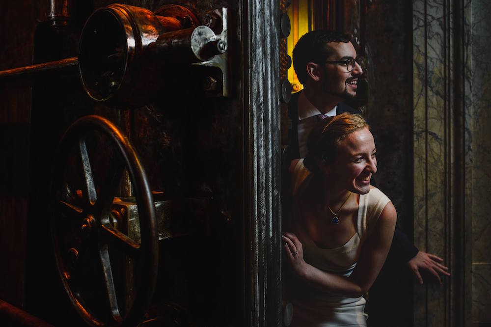 Photo of Lisa and David of Room Escape Artist in their wedding clothes dramatically escaping a bank vault.