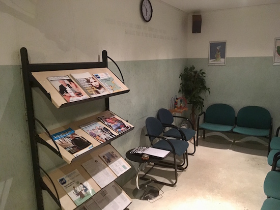 In-game: the lobby with a magazine wrack, chairs, and a stack of in-take forms.