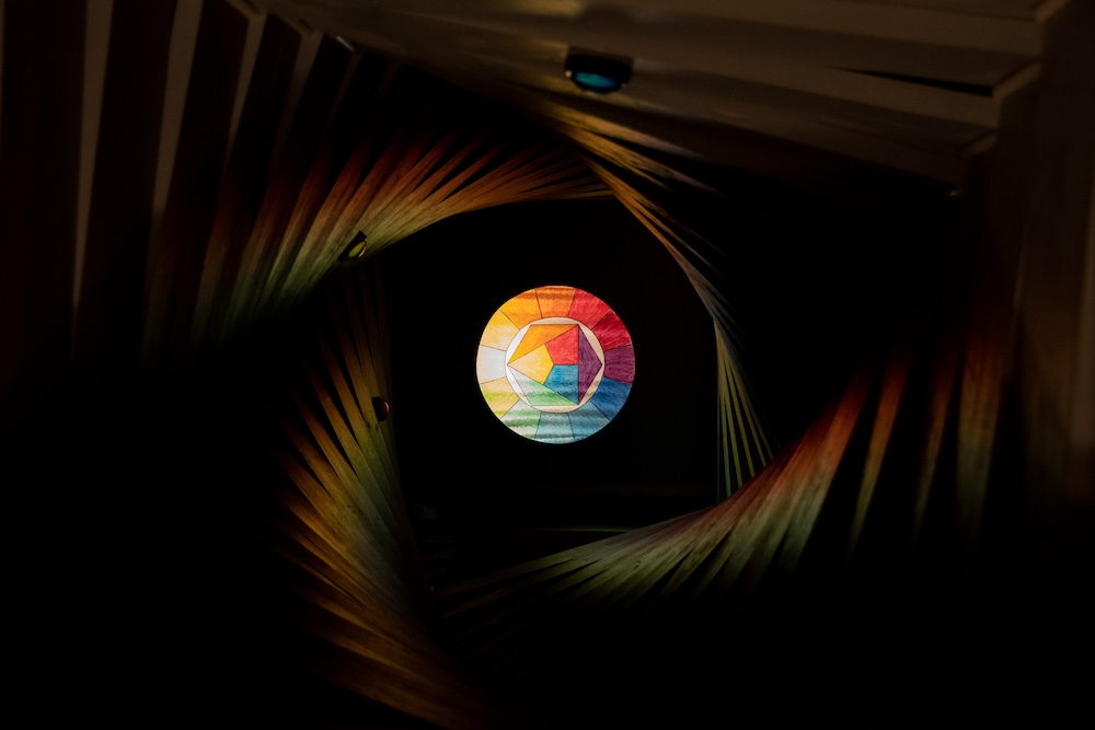 A geometrical, twisty tunnel with a colorful glowing image at the far end.