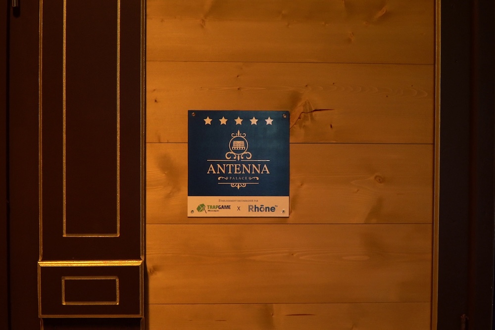 A sign mounted to a wooden wall with 5 stars reads, "Antenna Palace"