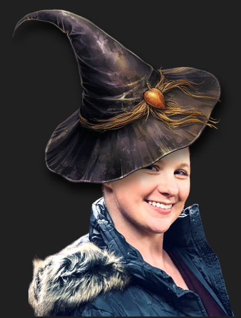 woman smiling with a black jacket and furry hood. She is wearing a cartoon witch hat