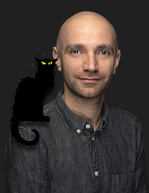 man with shaved head in a grey button down shirt with a cartoon cat on his shoulder