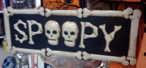 a halloween sign made of bones arranged in a rectangular shape. Inside it says "spoopy" the letters look like bones and the "o's" are skulls.